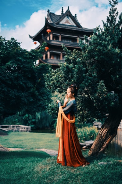 白天站在棕色木屋附近的一个穿着橙色衣服的女人